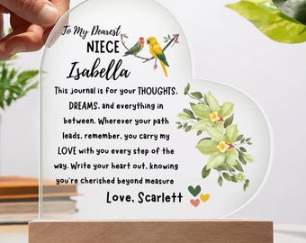 Puede incluir: Placa acrílica en forma de corazón con base de madera, con texto dirigido a "Isabella" de "Scarlett". La placa incluye un diseño floral y dos pájaros posados en una rama. El texto dice "This journal is for your THOUGHTS."