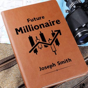 Peut inclure: Un carnet en cuir marron avec le texte "Future Millionaire" et un graphique boursier noir et blanc avec une flèche ascendante. Le nom "Joseph Smith" est imprimé sous le graphique.