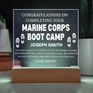 May include: A lighted acrylic plaque with a wooden base. The plaque reads "CONGRATULATIONS ON COMPLETING YOUR MARINE CORPS BOOT CAMP JOSEPH SMITH." Includes a message of support and is signed "Love, Sarah."