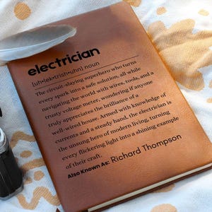 May include: A brown leather journal with the word "electrician" embossed on the front. The journal also includes a definition of the word and the text "Also Known As: Richard Thompson".