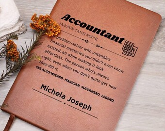 May include: A brown leather journal with the word "Accountant" defined as a "problem-solver who untangles financial mysteries" and the name "Michela Joseph" written below.