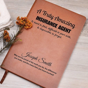 Puede incluir: Un diario de cuero marrón con el texto "A Truly Amazing INSURANCE AGENT" y personalizado con el nombre "Joseph Smith". El diario incluye la cita "Is hard to find, difficult to part with, & impossible to forget."