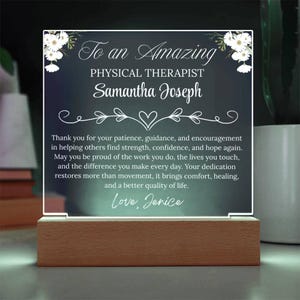 May include: A clear acrylic plaque with the text "To an Amazing PHYSICAL THERAPIST Samantha Joseph" and a message of appreciation. The plaque is set on a wooden base and decorated with floral accents.
