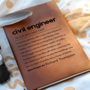 Op de afbeelding: Een bruin lederen notitieboek met de definitie van een civiel ingenieur op de omslag. De definitie luidt: "Een meesterplanner die wilde dromen van wolkenkrabbers, snelwegen en bruggen in de realiteit omzet, gewapend met niets anders dan een helm, een rekenmachine en een eindeloze voorraad koffie. Ze jongleren met blauwdrukken, budgetten en bureaucratische hindernissen, terwijl ze er tegelijkertijd voor zorgen dat de wegen waar je over rijdt en de gebouwen waar je in woont niet in een hoop puin uiteenvallen. Ook bekend als: Richard Thompson"