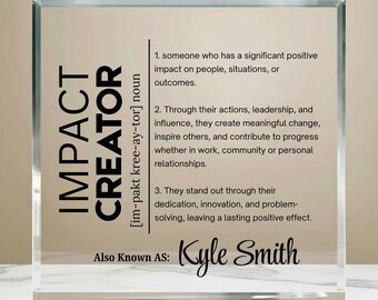 Pode incluir: Um bloco de vidro transparente com as palavras "IMPACT CREATOR" em letras pretas em negrito. O bloco inclui uma definição de "Impact Creator" e o nome "Kyle Smith" em escrita elegante. O fundo é bege neutro.