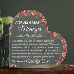 May include: A heart-shaped acrylic plaque with floral accents. The text reads "A Truly Great Manager" and includes a personalized name. The design features a decorative floral border with red and orange flowers.