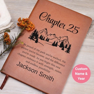 May include: A brown leather journal with the text "Chapter 25" and a mountain and tree design. The journal also features the name "Jackson Smith" and a quote. A pink circle indicates custom name and year options.