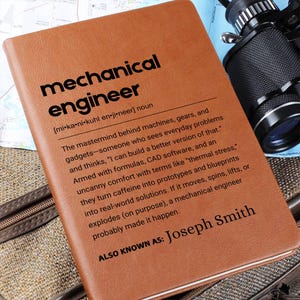 May include: A brown leatherette notebook with the words "mechanical engineer" in bold black letters. The definition of a mechanical engineer is printed below the title, along with the name "Joseph Smith."