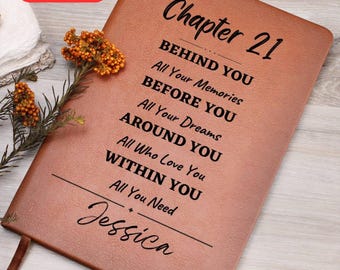 Może przedstawiać: Brązowy skórzany notatnik z tekstem "Chapter 21" i inspirującymi frazami. Imię "Jessica" jest wygrawerowane na dole. Czerwony prostokąt w lewym górnym rogu głosi "BEZPŁATNA PERSONALIZACJA NA DOWOLNY ROK."