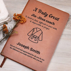 Può includere: Un diario rilegato in pelle marrone con il testo "A Truly Great Jiu-Jitsu coach" e un grafico di un'uniforme di Jiu-Jitsu. Il diario include anche il nome "Joseph Smith" e un messaggio sincero.