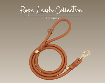 May include: A tan rope leash with gold-colored hardware. The leash has a loop at the top and a clasp at the bottom. The text "Rope Leash Collection" and "STYLPETZ" are in the image.