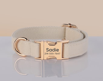 May include: Cream-colored dog collar with a gold-colored buckle and hardware. The buckle has the name "Sadie" and a phone number engraved on it. The collar is made of a soft, woven material.
