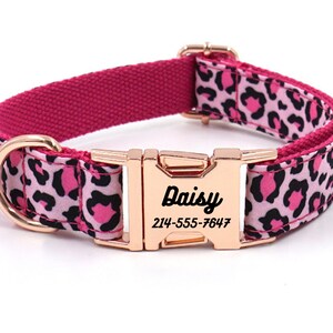 Pode incluir: Coleira de cão com estampa de leopardo rosa e preto com fivela de ouro rosa e uma etiqueta de nome personalizada que diz "Daisy" e um número de telefone.
