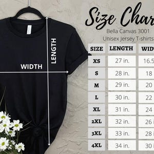 Puede incluir: Camiseta negra colgada de una percha negra, con una tabla de tallas para camisetas unisex Bella Canvas 3001. La tabla enumera las tallas XS a 4XL, con medidas de largo y ancho en pulgadas.