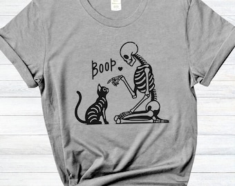 May include: A gray t-shirt with a black skeleton and cat design. The skeleton is pointing at the cat and saying "Boop".