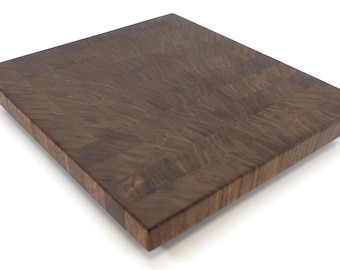 May include: A large, dark brown wooden cutting board with a butcher block design. The board is made of solid wood and has a smooth, polished surface.