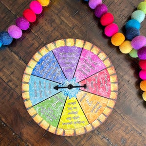 May include: A colorful game board with a spinning arrow. The board has different colored sections with text such as "Spin again on your next turn", "Win all Fountain of Life prizes", "Extra turn every time you land on blue", "Switch places with the player in 1st", "Move forward 7 spaces", "Make any player move back 7 spaces".