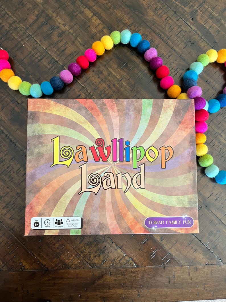 May include: A colorful board game box with the title "Lawllipop Land" and the text "Torah Family Fun". The box has a rainbow swirl design and a warning symbol.