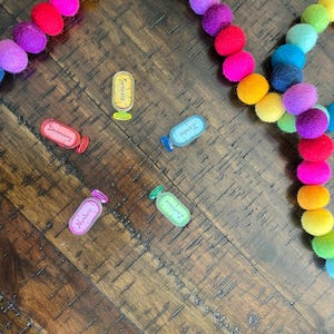 May include: A rainbow colored felt ball garland with five clear plastic bottles with labels that say "Genesis", "Deuteronomy", "Exodus", "Numbers", and "Joshua".