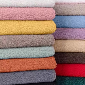 Può includere: Una pila di tessuti in pelliccia sintetica di diversi colori. I tessuti sono disposti in una pila, con il colore più chiaro in cima e il colore più scuro in fondo. I colori includono bianco, rosa, giallo, grigio, verde, marrone, rosso e nero.