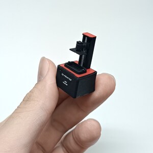 May include: A small black and red 3D printer with the text "3D PRINTER" and "OLP PRINTER" on the side.