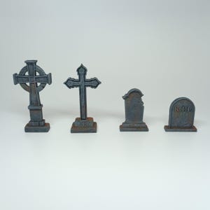 May include: Four miniature gray stone grave markers with a cross and the inscription "R.I.P."