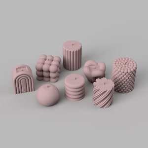 May include: A collection of eight pink candles in various shapes, including a cylinder with vertical ridges, a sphere, and a spiral design. The candles are arranged on a light gray surface, showcasing their unique textures and forms.