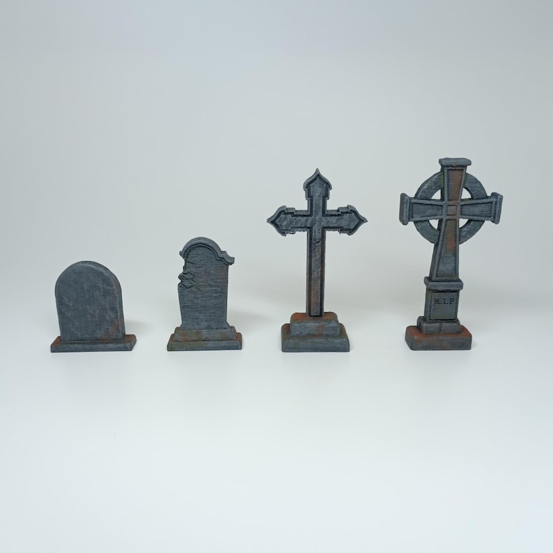 May include: Four miniature gray stone grave markers, two with crosses and two with rectangular headstones. One cross has a circle design and the words "R.I.P." on the base.