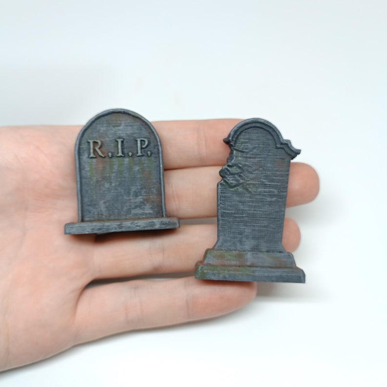 May include: Two miniature gray stone tombstones, one with the inscription "R.I.P." and the other with a chipped top.