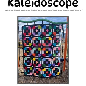May include: A colorful quilt with a kaleidoscope pattern, featuring squares of various colors, including black, white, red, blue, green, yellow, and pink. The quilt is hanging on a metal frame.