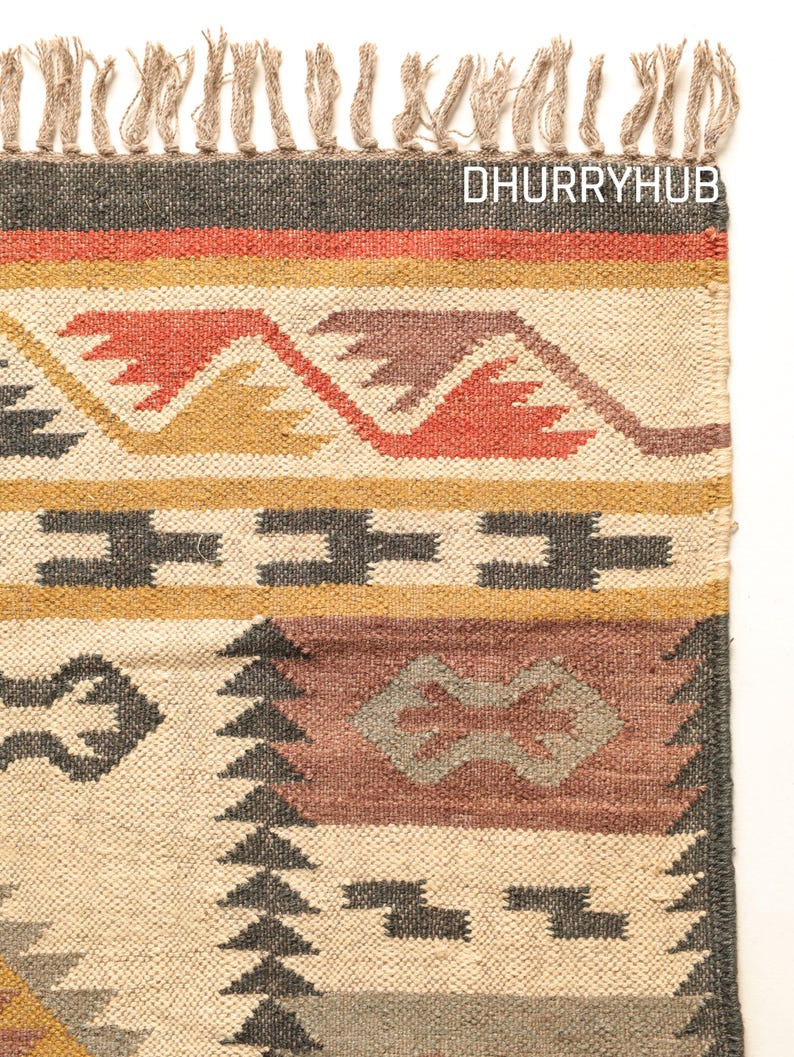 May include: A handwoven rug with a geometric pattern in shades of brown, red, and yellow. The rug has a fringe border and the text "DHURRYHUB" is visible in the top right corner.
