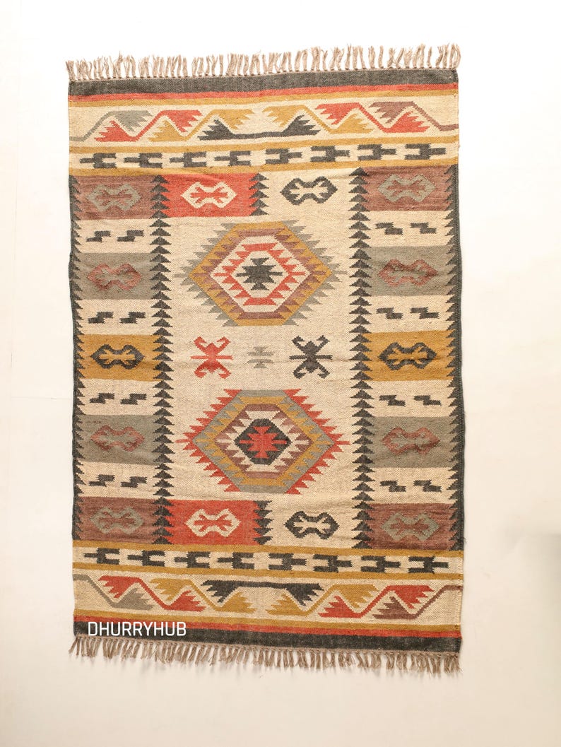 May include: A handwoven rug with a geometric pattern in shades of red, orange, yellow, black, and gray. The rug has a fringe border and is made of natural fibers.