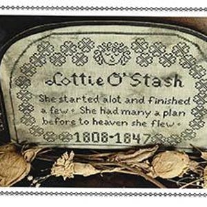 May include: A black and white cross-stitch embroidery design on a piece of fabric. The design is a tombstone with the text "Lottie O'Stash" and the dates "1808-1847". The text reads "She started alot and finished a few. She had many a plan before to heaven she flew."