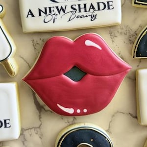 May include: A set of decorated sugar cookies featuring a red lip, a syringe, and the text "A New Shade of Beauty".