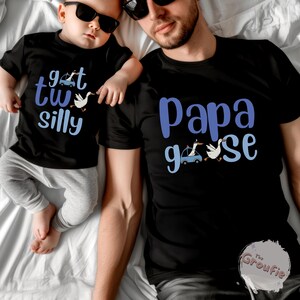 May include: Black t-shirts with matching designs. One shirt says "get two silly" with a car and goose graphic, the other says "Papa goose" with a car and goose graphic. Both shirts have blue text.