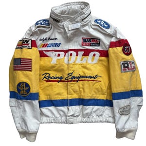 May include: White, yellow, and blue racing jacket with multiple patches and the text "POLO Racing Equipment." Features the American flag and the number "67." The jacket has a stand-up collar and a zip-up front.