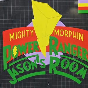 Puede incluir: Un recorte de papel colorido con el texto "MIGHTY MORPHIN POWER RANGERS JASON'S ROOM". El diseño incluye un rayo amarillo, texto rojo y verde, y un círculo morado, todo sobre un fondo de cuadrícula negra.