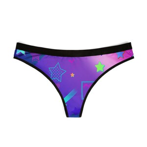 May include: A pair of underwear with a vibrant, colorful design. The underwear features a purple gradient background with neon stars, geometric shapes, and a black waistband. The overall aesthetic is reminiscent of the 1980s.