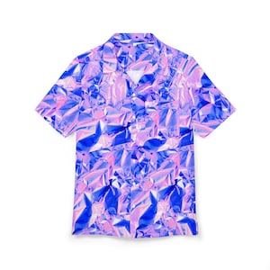 Puede incluir: Camisa de manga corta con un llamativo diseño abstracto. El patrón combina tonos de azul, rosa y morado, creando un efecto brillante, similar al papel de aluminio. La camisa tiene un cuello clásico y un corte relajado.