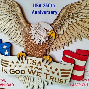 May include: A wooden laser-cut design featuring an American bald eagle with outstretched wings. The eagle holds a banner with the text "USA 1776-2026 IN GOD WE TRUST." The design includes blue and red flag elements, with the text "USA 250th Anniversary."