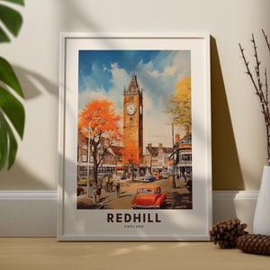 May include: A vintage-style poster featuring a colorful illustration of a town square in Redhill, England. The poster depicts a clock tower, buildings, trees, and people walking down the street. A red car is parked in the foreground. The text "REDHILL ENGLAND" is printed at the bottom of the poster.