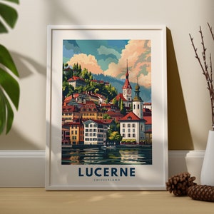 May include: A framed art print featuring a colorful illustration of Lucerne, Switzerland. The artwork depicts buildings with red rooftops, a church with a tall steeple, and a lake. The word "LUCERNE" is printed in navy blue at the bottom.
