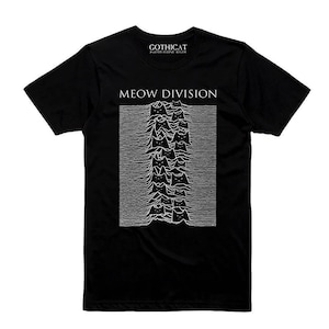 Può includere: T-shirt nera con grafica bianca raffigurante sagome di gatti disposte a onde, con la scritta "MEOW DIVISION" sopra. La maglietta presenta anche la scritta "GOTHICAT" in alto.