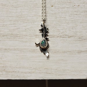 Op de afbeelding: Een zilveren ketting met een hanger met een groene opaal-steen in een zilveren bladontwerp.