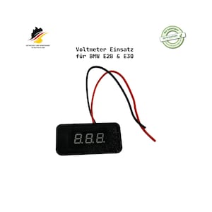 Könnte beinhalten: Ein schwarzes Voltmeter mit einer Digitalanzeige, die "8.8.8." anzeigt, und roten und schwarzen Drähten. Der Text "Voltmeter Einsatz für BMW E28 & E30" befindet sich über dem Voltmeter. Das Bild enthält auch eine deutsche Flagge und ein grünes kreisförmiges Logo.