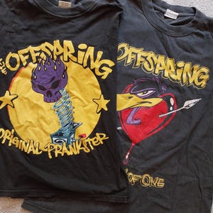 May include: Two black Offspring band t-shirts. One features a purple skull on a yellow circle with the text "Original Prankster." The other has a cartoon bird with a heart and the text "One of One."