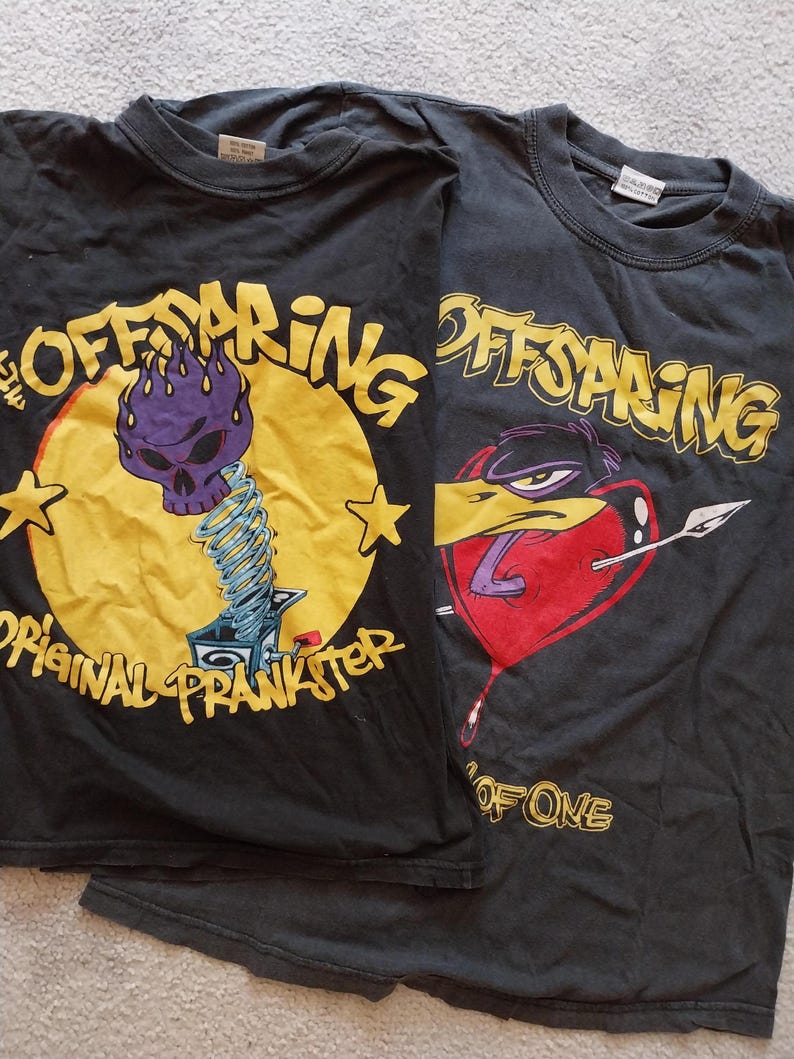 May include: Two black Offspring band t-shirts. One features a purple skull on a yellow circle with the text "Original Prankster." The other has a cartoon bird with a heart and the text "One of One."