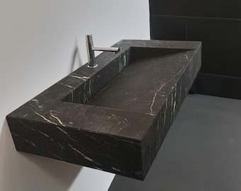 May include: A black marble bathroom sink with a rectangular shape and a single faucet. The sink is mounted on a wall and has a white veining pattern.