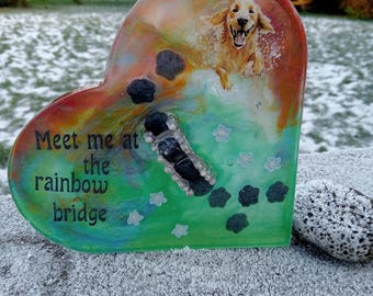 May include: A heart-shaped resin memorial with a photo of a golden retriever running. The background is a green and orange swirl. The text "Meet me at the rainbow bridge" is written on the bottom.