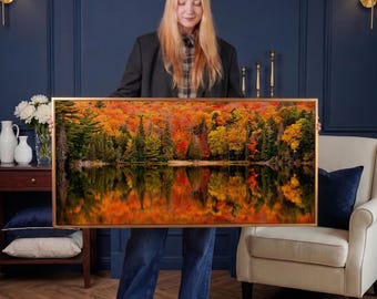 May include: A framed landscape art print featuring a vibrant autumn scene. The artwork showcases a lake reflecting colorful trees in shades of red, orange, and yellow. The frame is a warm gold color, enhancing the natural beauty of the forest.